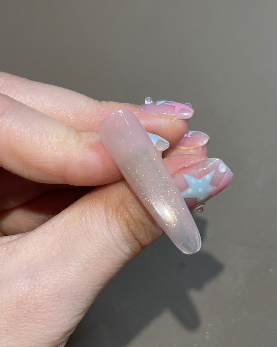 Ein Pinsel trägt einen klaren Top Coat auf den fertig magnetisierten und schimmernden Cat-Eye-Nagel auf.