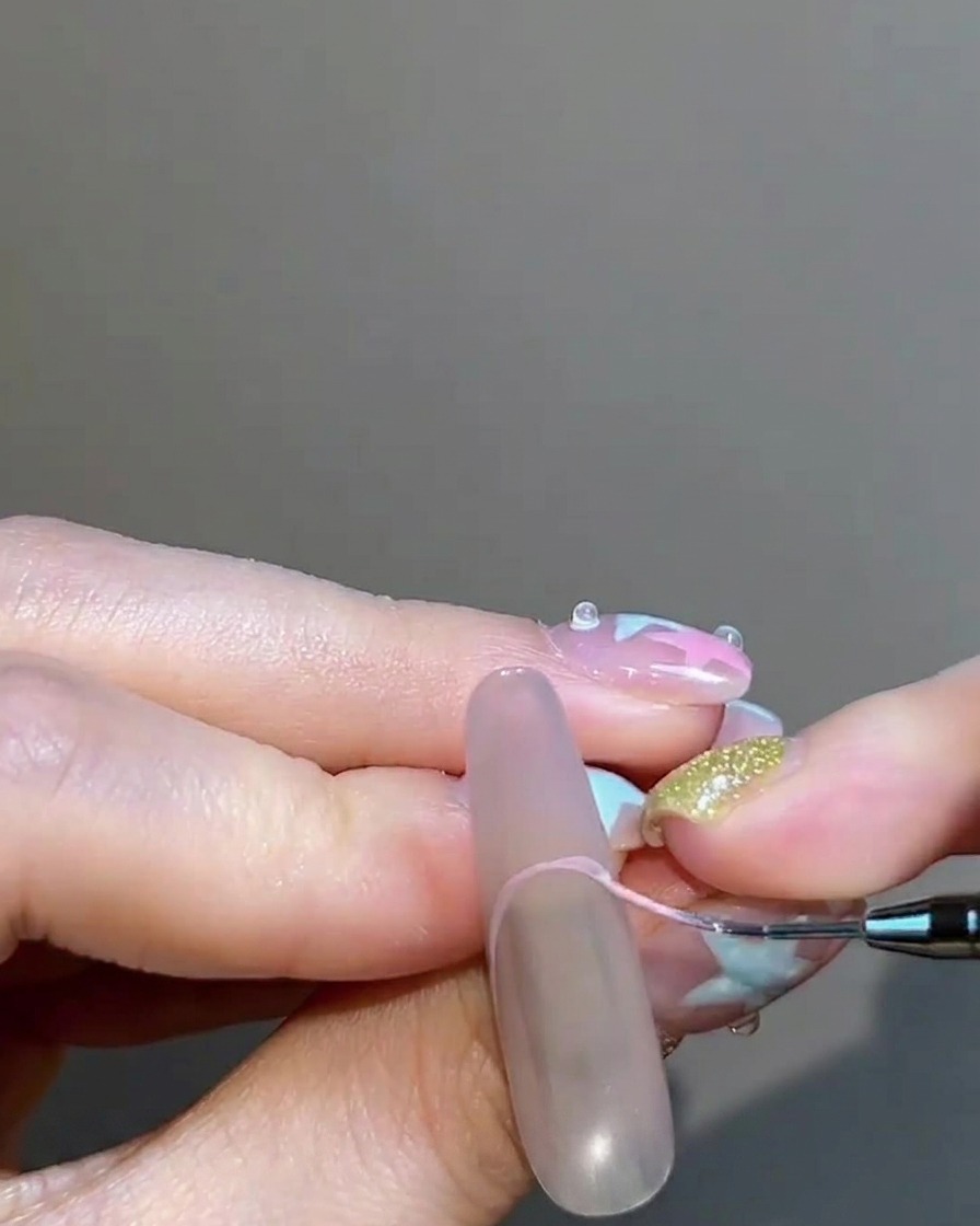 Ein feiner Liner-Pinsel malt vorsichtig eine rosige Nude-Gel French-Spitze auf den Nagel.