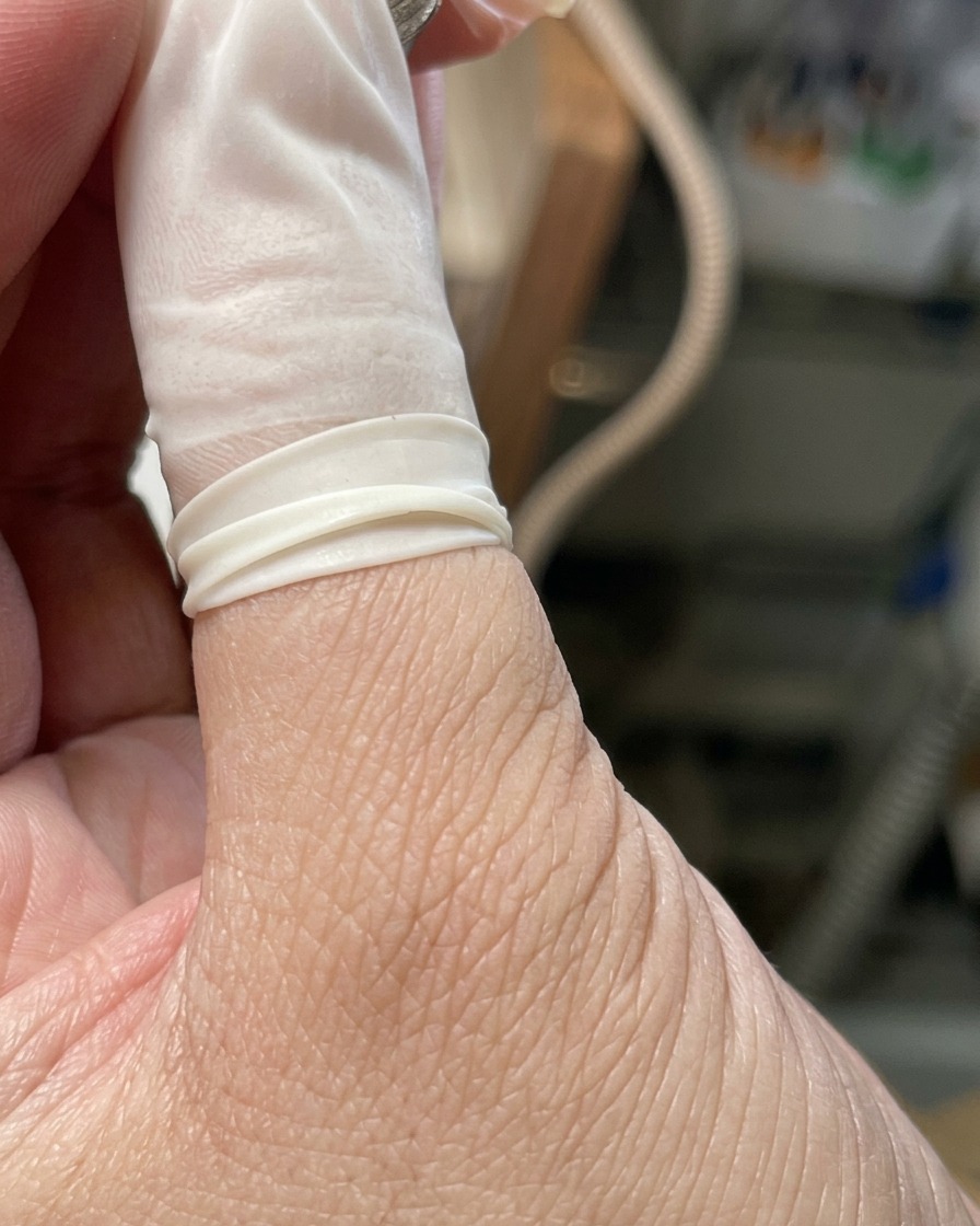 Eine Hand ruht in einer professionellen UV/LED-Nagellampe mit aktiviertem Licht.