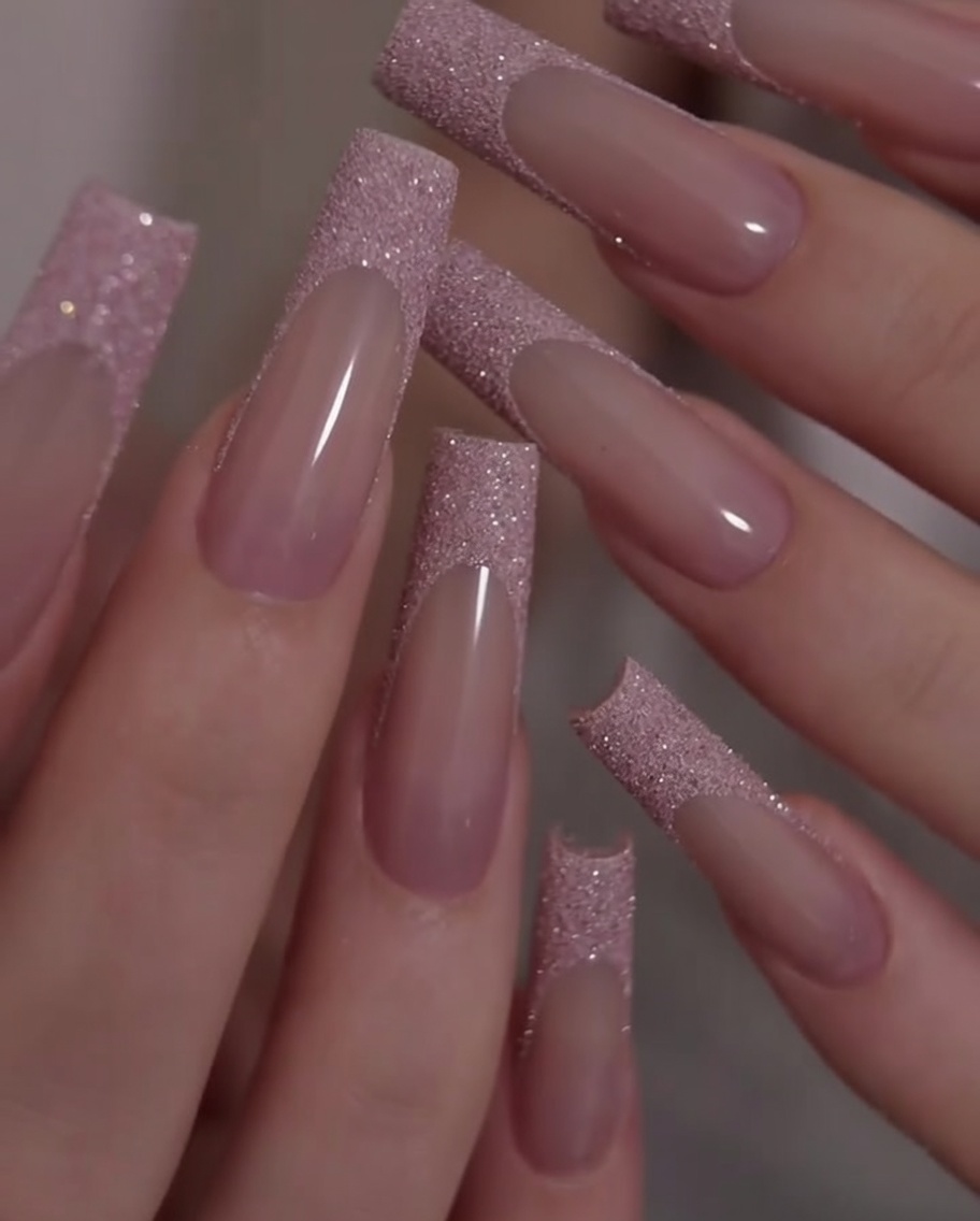Nahaufnahme von Händen, die leicht gedreht werden, um den Kontrast zwischen rosa Basis und Glitzerspitzen zu zeigen.