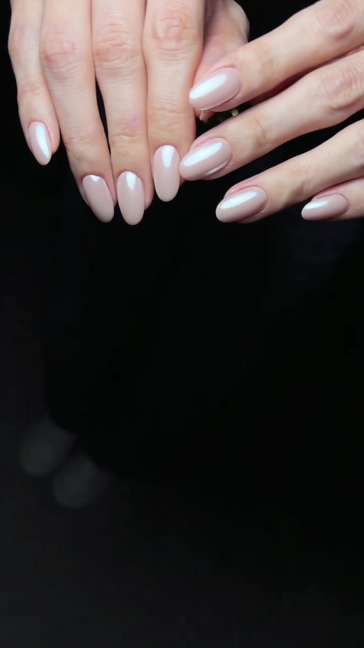 Nahaufnahme von eleganten, mandelförmigen Nägeln mit einer Basis aus zartem Rosé-Gel und einem leuchtenden Perlmutt-Chrome-Finish.