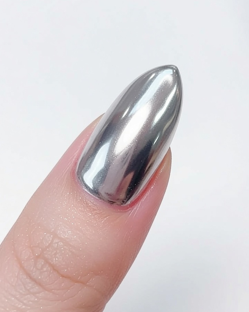 Ein weicher Pinsel wird verwendet, um loses silbernes Chrom-Puder von einem fertigen Nagel mit Spiegeleffekt zu entfernen.
