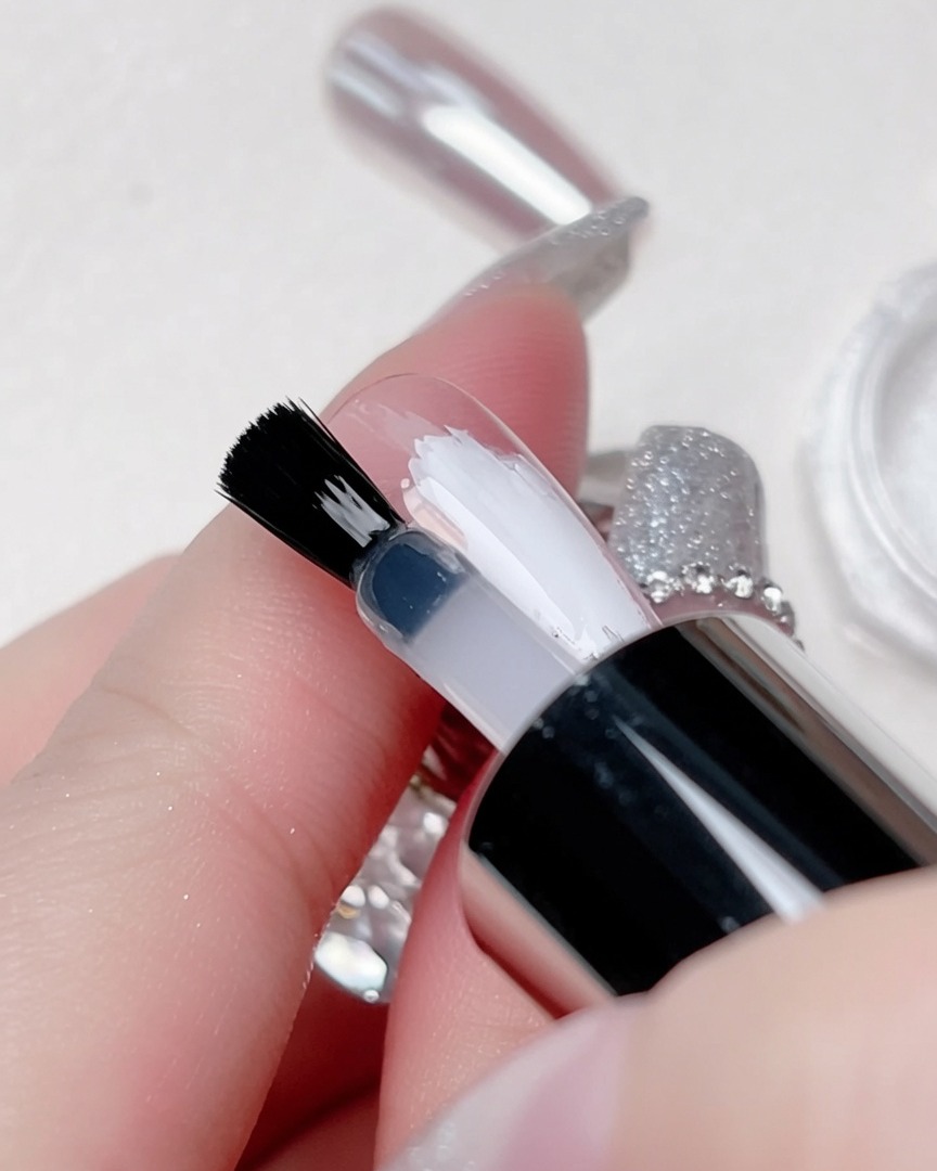 Ein dünner, klarer Top Coat wird mit einem Pinsel gezielt über den weißen Mittelstreifen aufgetragen.