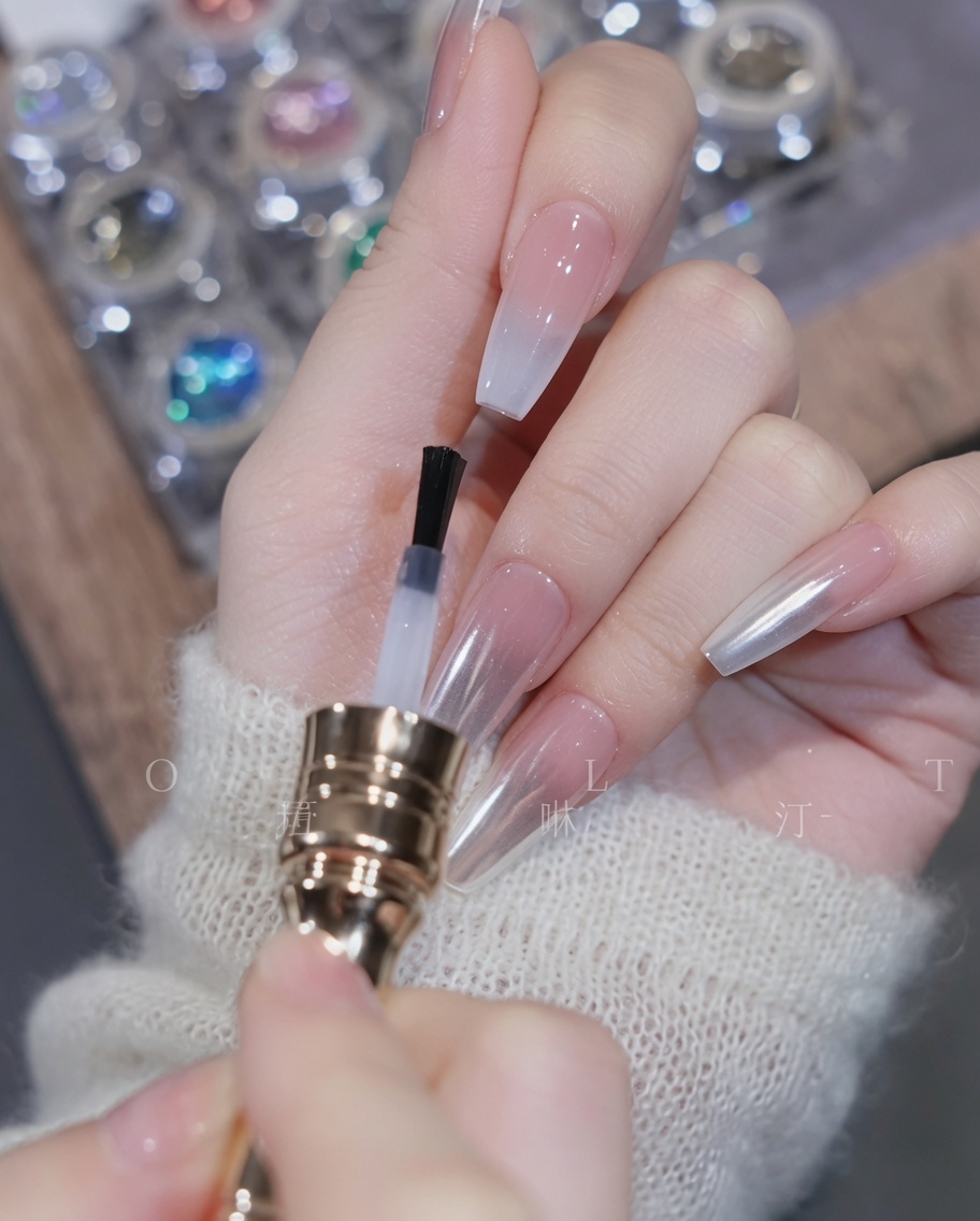 Ein Pinsel trägt einen klaren Top Coat über dem fertigen Gradient-Nagel auf.