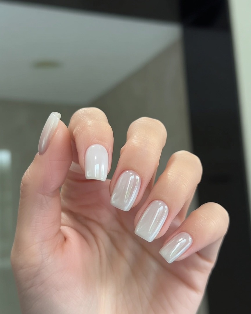 Ein Pinsel, der eine durchsichtige Top-Coat-Schicht über Nägel mit einem Pearl-Chrome-Finish aufträgt.
