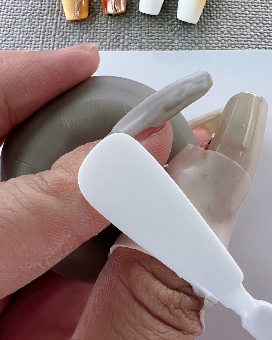 Ein Pinsel trägt gleichmäßiges, weißes Gel-Polish auf die Nageloberfläche auf.