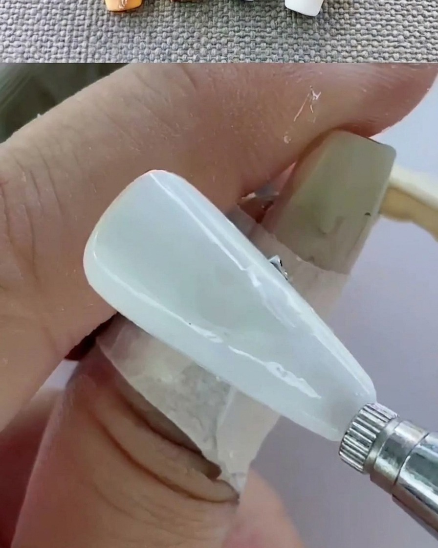 Nahaufnahme einer Hand in einer UV-Lampe beim Aushärten der Nägel.