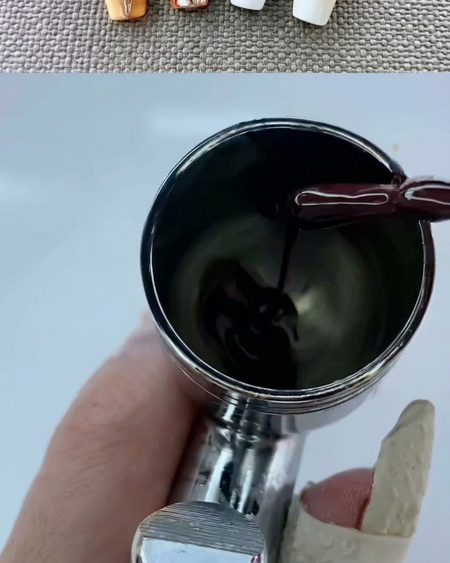 Ein Airbrush-Gerät erzeugt einen sanften, warmen Farbverlauf auf einem weißen Nagel.