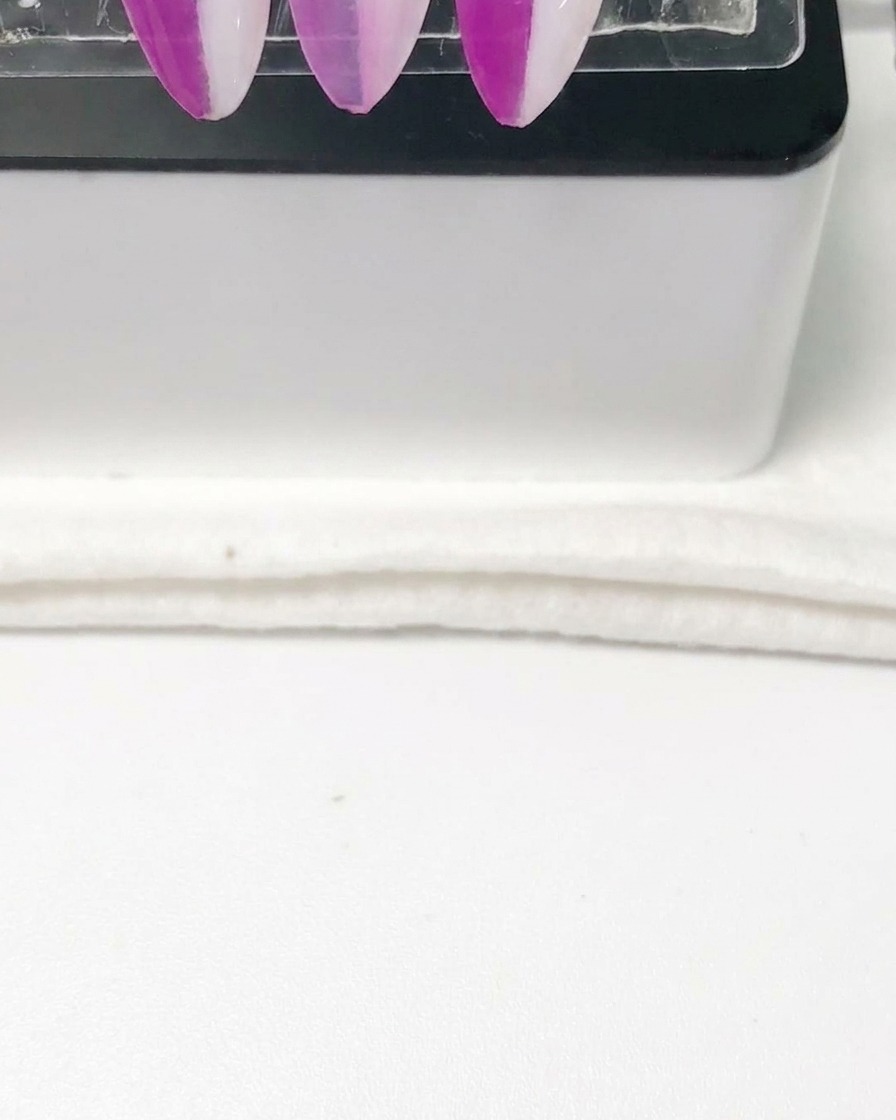Eine Pipette gibt klare Verdünnungsflüssigkeit in den Metallbecher einer Airbrush-Pistole.