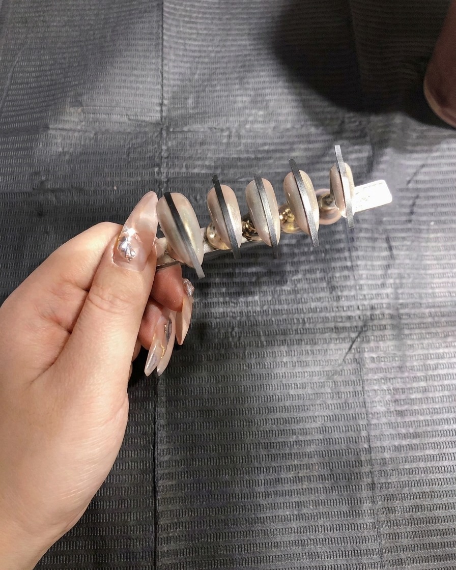 Eine Airbrush-Pistole trägt die erste Schicht weißes Sprühgel auf das zweite Nagelset auf.