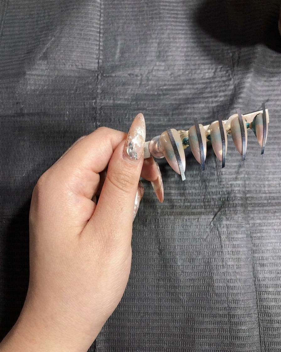 Ein Nagelständer mit künstlichen Nägeln wird zum Aushärten in eine UV-Lampe gestellt.