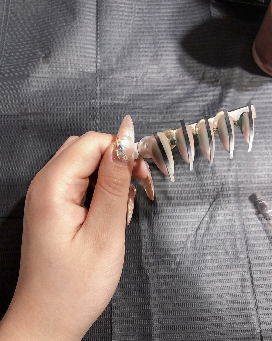 Künstliche Nägel auf einem Ständer härten unter dem hellen Licht einer UV-Nagellampe aus.