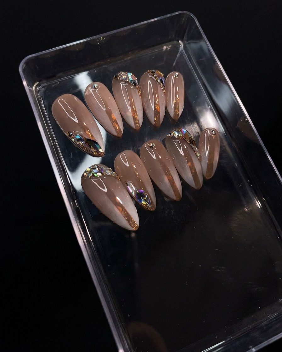 Ein Nagelpinsel trägt einen klaren, glänzenden Top Coat über dem detaillierten Gradienten- und Strass-Design auf.