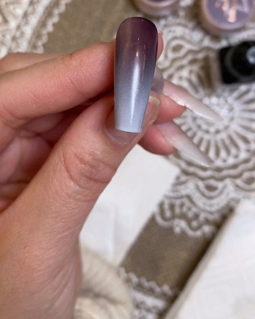 Eine Airbrush sprüht die finale, intensivierte weiße Schicht auf den Nagel.
