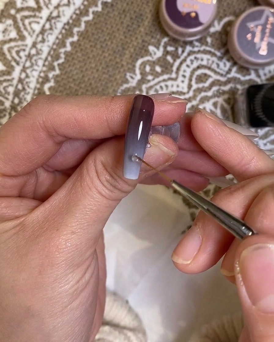 Ein feiner Liner-Pinsel verblendet den Übergangsbereich auf dem Nagel.