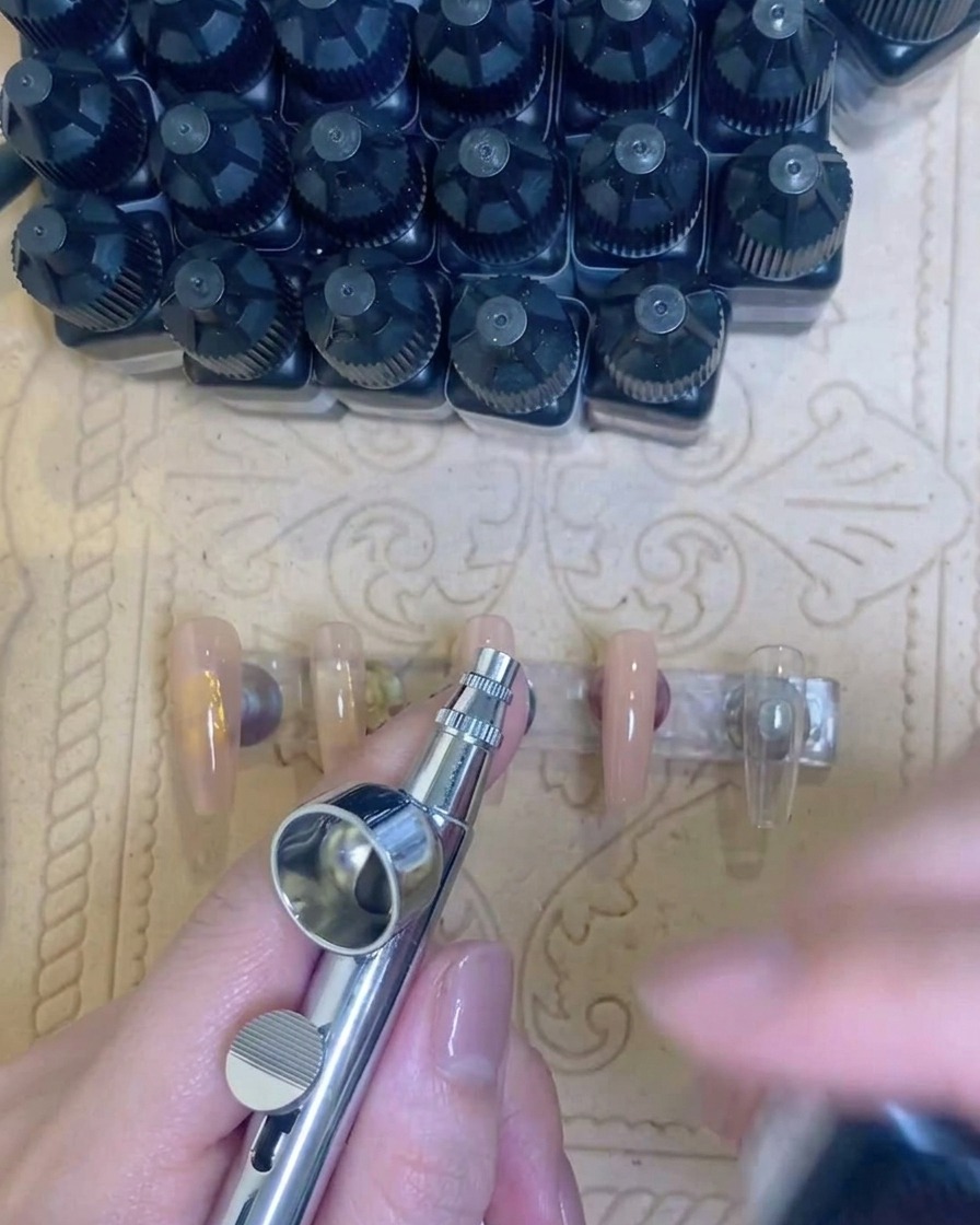 Eine Airbrush-Pistole, die eine Testlinie aus weißem Pigment auf ein Papiertuch sprüht.