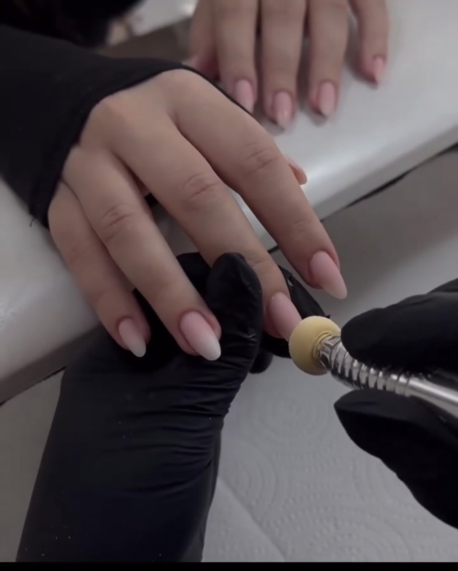Nahaufnahme eines Schwammapplikators, der perlmuttartiges Chrome-Puder auf die Spitze des Mittelfingers tupft.