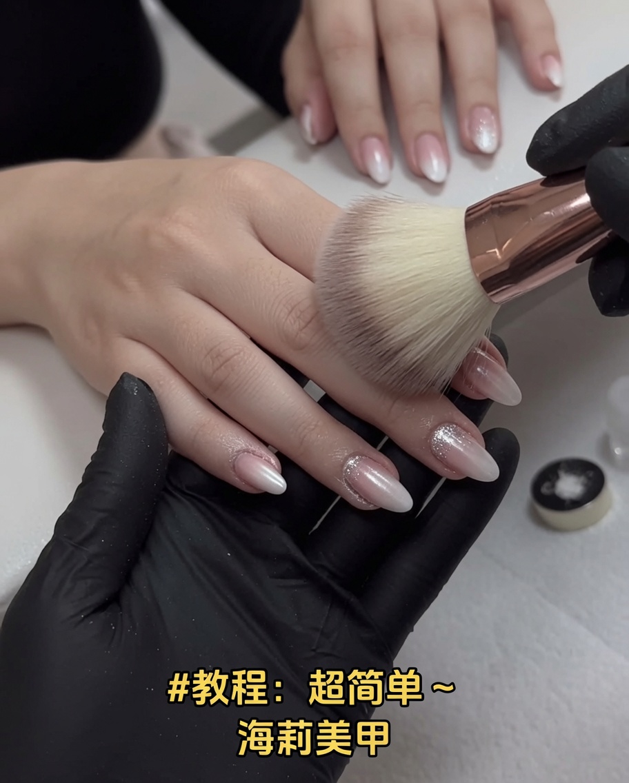 Ein großer, weicher, rosafarbener Make-up-Pinsel streicht über manikürte Fingernägel, um überschüssigen Chrome-Staub zu entfernen.