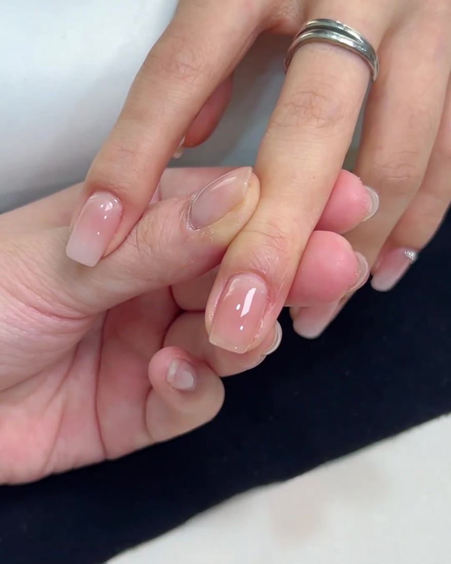 Eine Nahaufnahme eines quadratischen Nagels mit einer gleichmäßig aufgetragenen Schicht aus nudefarbenem Gel-Lack.