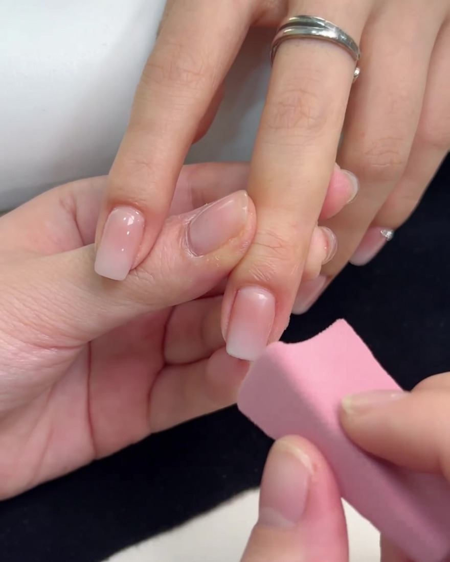 Ein kleiner rosa Schwamm tupft weißes Gel auf die Nagelspitze, um den Ombré-Effekt zu verstärken.
