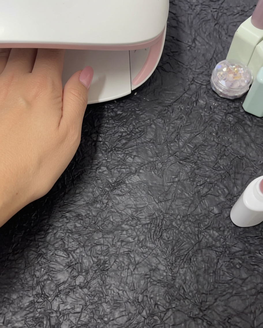 Eine Hand, die zum Aushärten in einer weißen UV/LED-Nagellampe liegt.