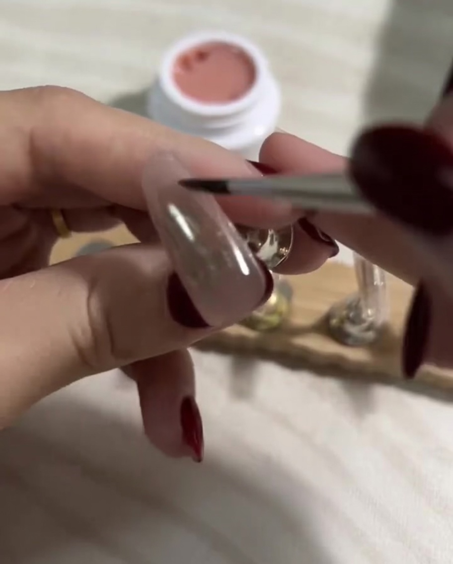 Auftragen einer glatten Schicht helles Nude-Gel über die bereits gehärtete dunkle Basisschicht auf einem Press-On-Nagel.