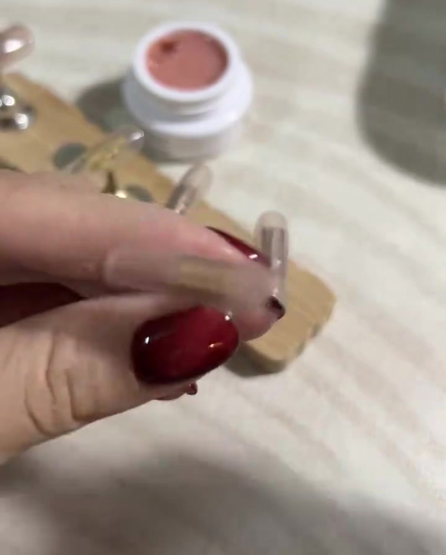 Nahaufnahme einer Hand, die mit einem fusselfreien Tuch und Gel-Reiniger die Oberfläche der gehärteten Press-On-Nägel säubert.