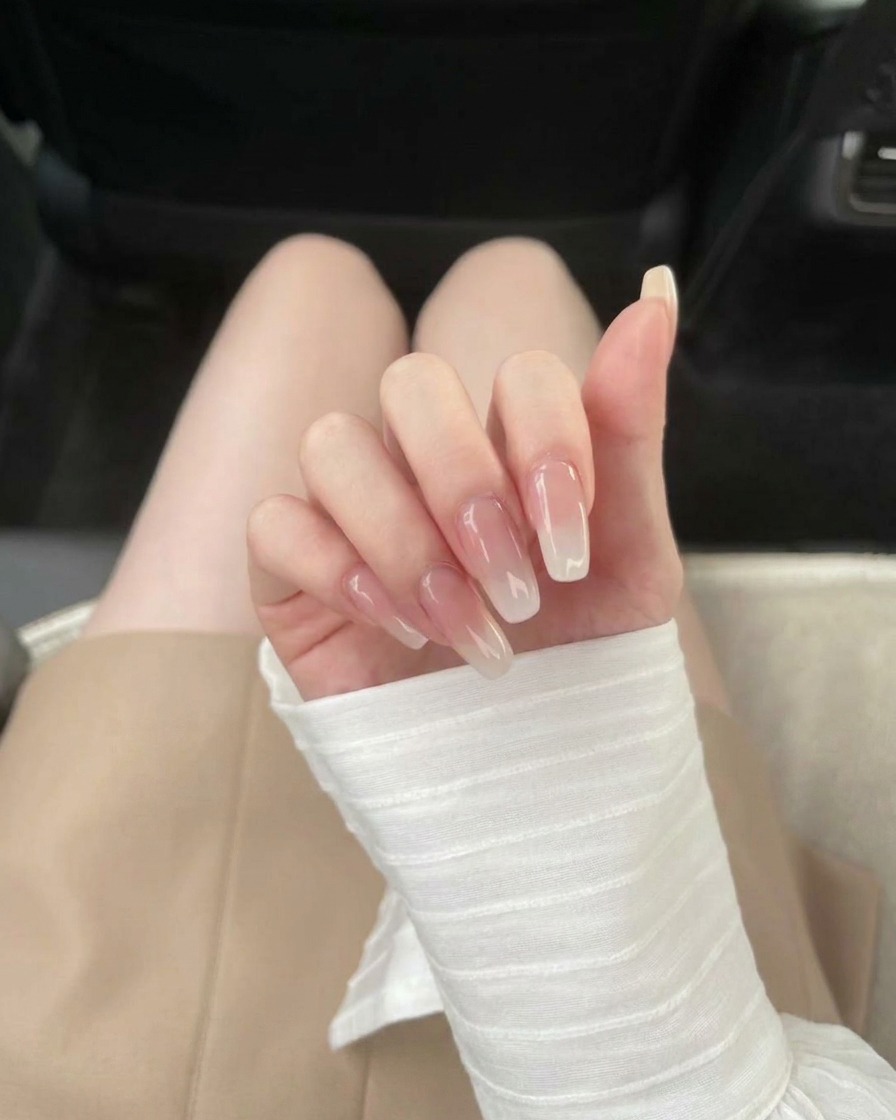Ein Pinsel trägt klaren Base Coat auf eine transparente Nagelverlängerung auf.