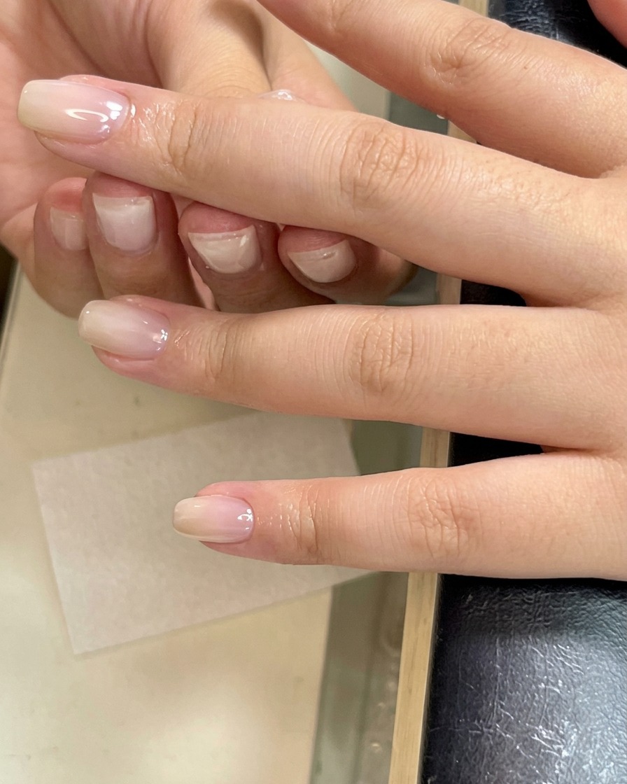 Eine Hand reinigt die Oberfläche eines gerade gehärteten Nagels mit einer Zellette.