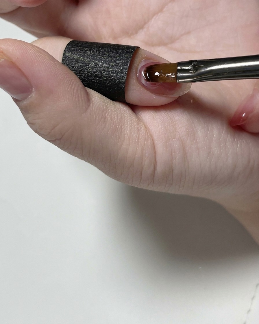 Ein feiner Detailpinsel glättet das klare Struktur-Gel nahe der Nagelhaut.