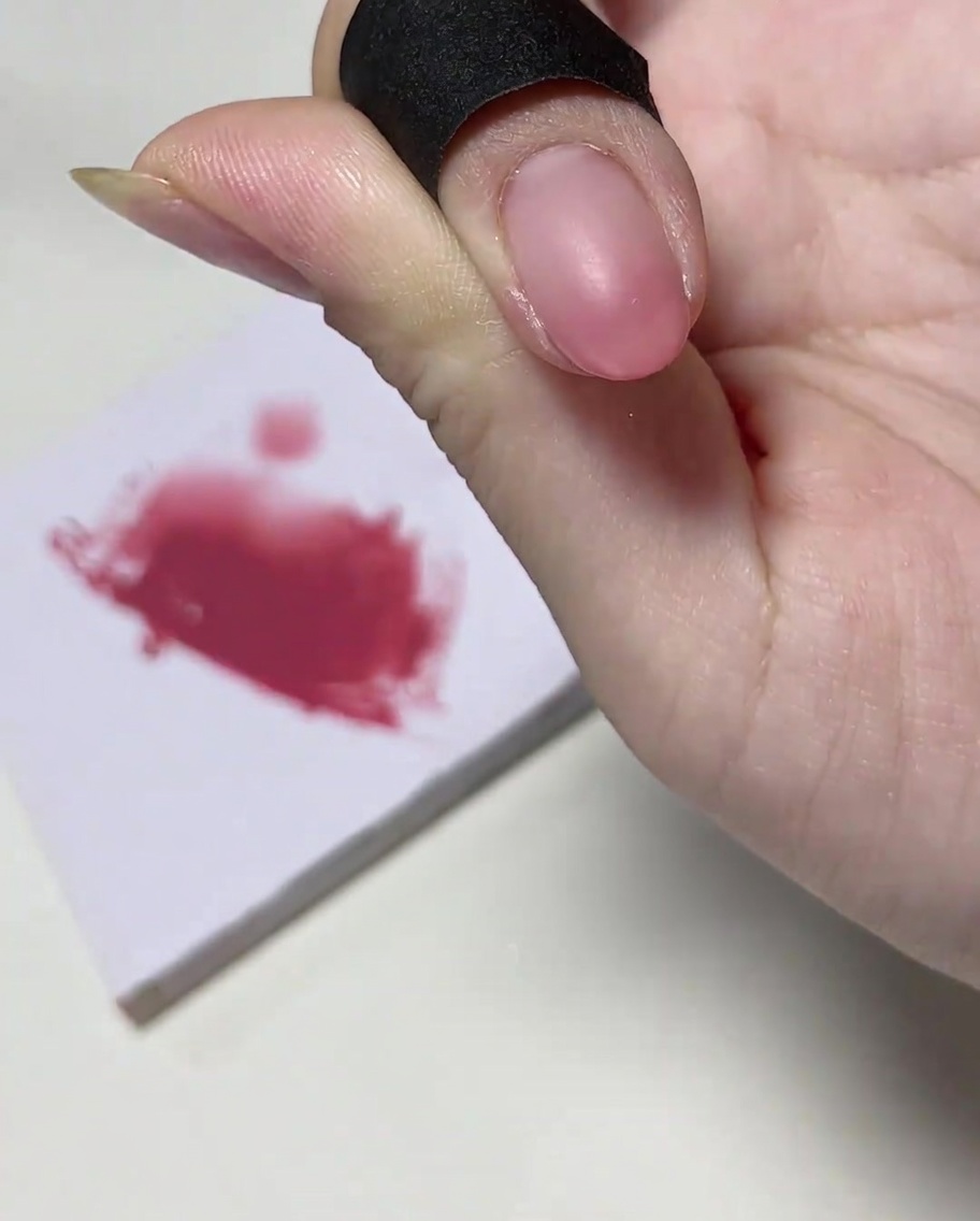 Ein Nagelpinsel gibt eine konzentrierte Menge rosa Farbgel auf die Nagelspitze.
