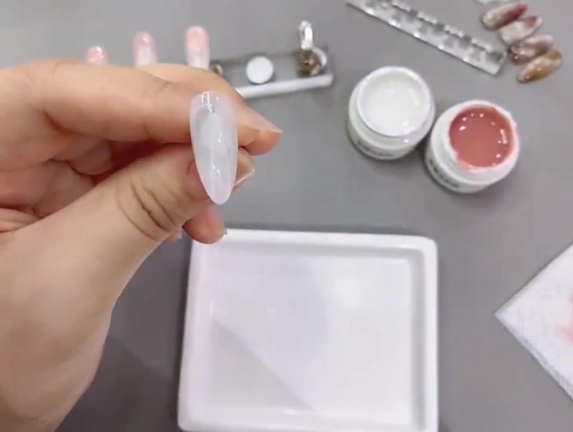 Ein Nageltip erhält eine zweite Aushärtung unter der Lampe.
