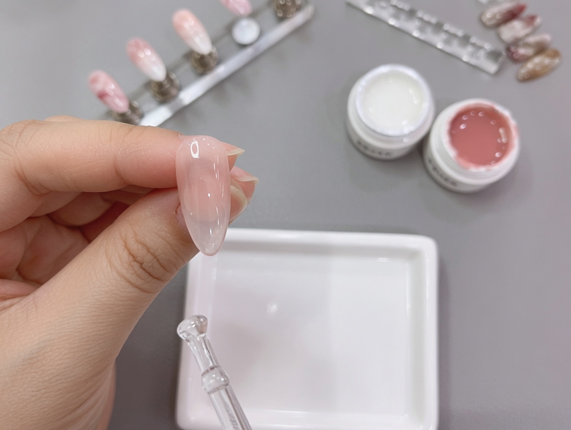 Nahaufnahme einer Hand mit einem fertigen Nude-zu-Weiß-Verlaufsdesign, die für die finale Aushärtung unter eine UV-Lampe gelegt wird.