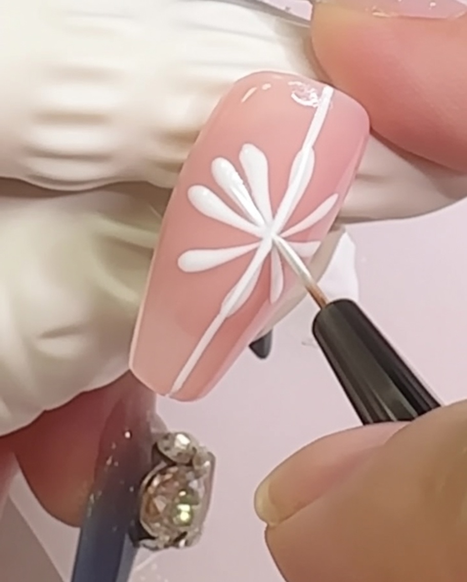 Ein Nagel mit einem Gänseblümchen-Design, bei dem kleine, abgerundete Blütenblattformen an den Enden der Linien ergänzt wurden.