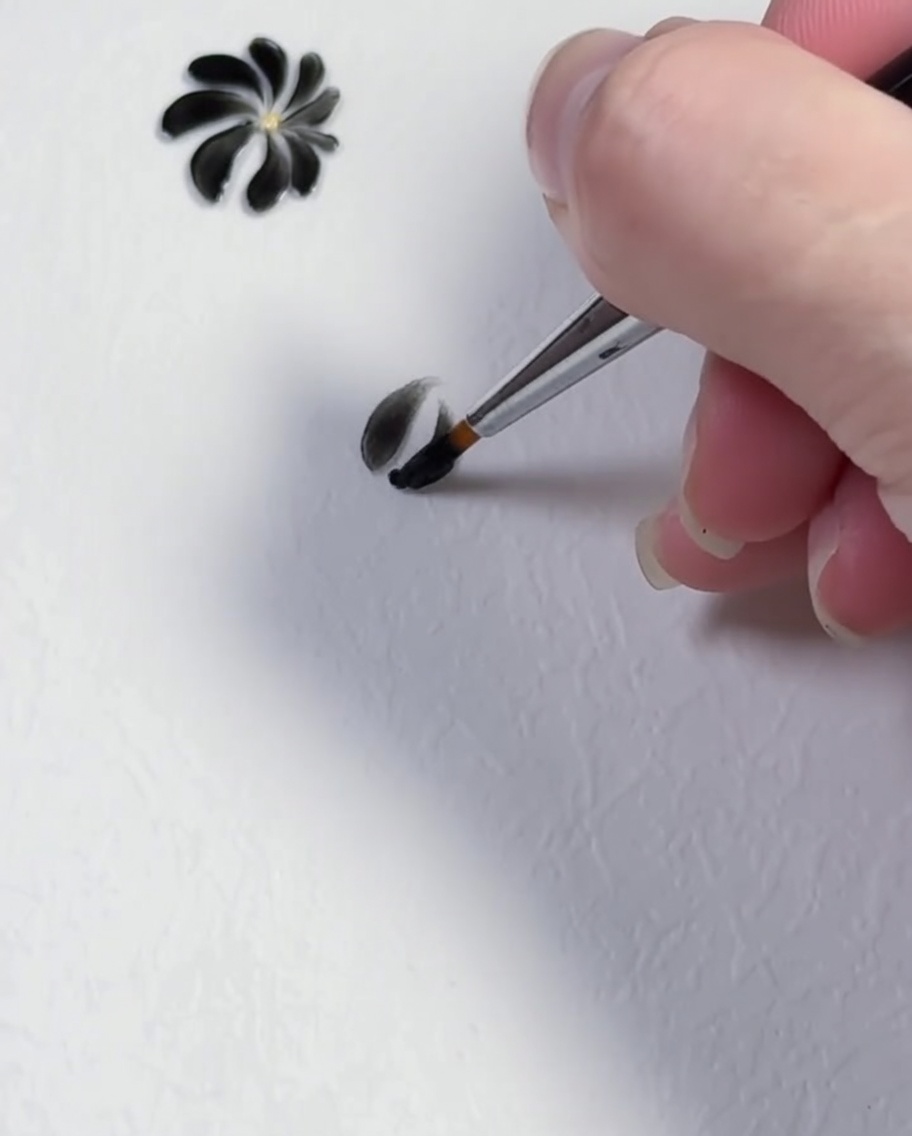 Ein Pinselstrich formt das dritte schwarze Blütenblatt eines Gänseblümchen-Designs.