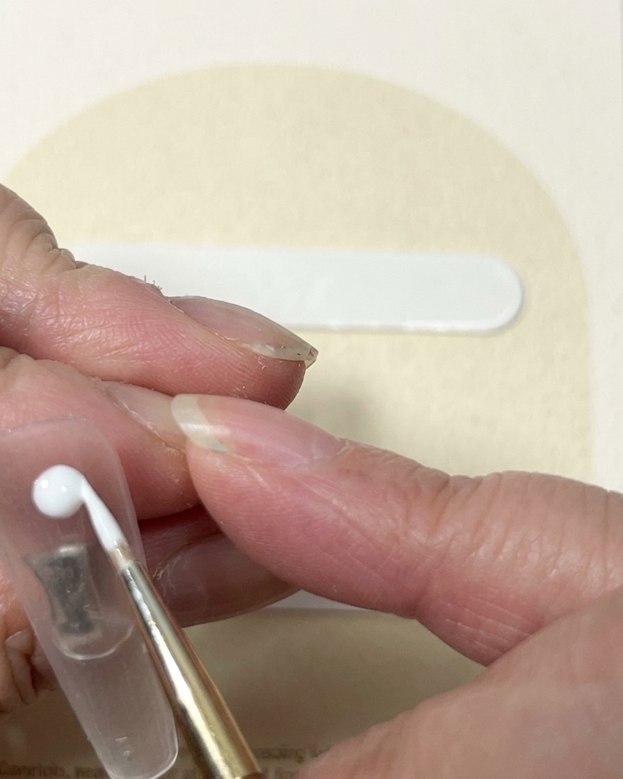 Ein Liner-Pinsel zieht weißes Gel von einem zentralen Punkt weg, um die wirbelnde Optik einer Rosenknospe zu erzeugen.