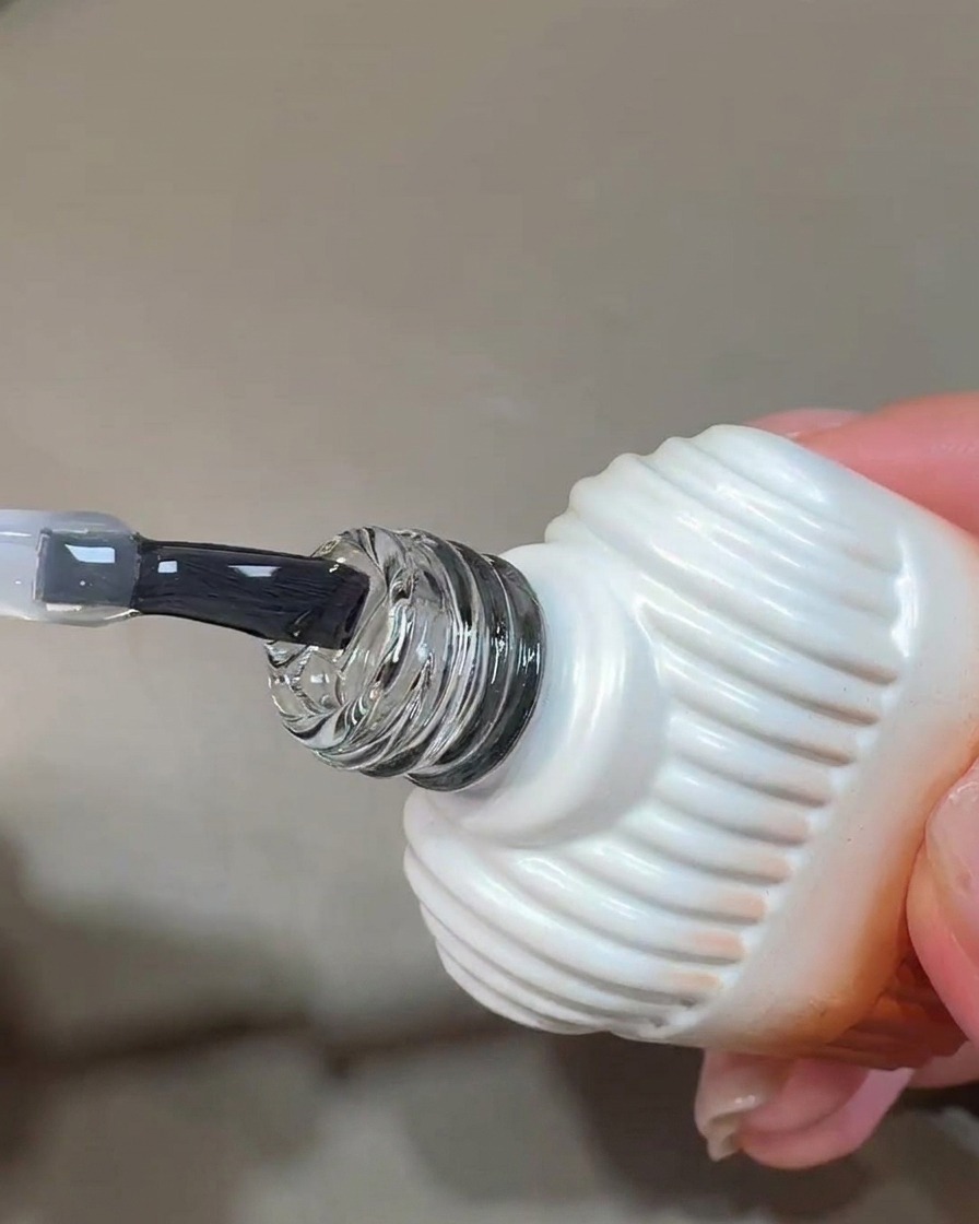 Ein Pinsel trägt eine klare, glänzende Schicht Blooming Gel auf einen vorbereiteten Nagel auf.