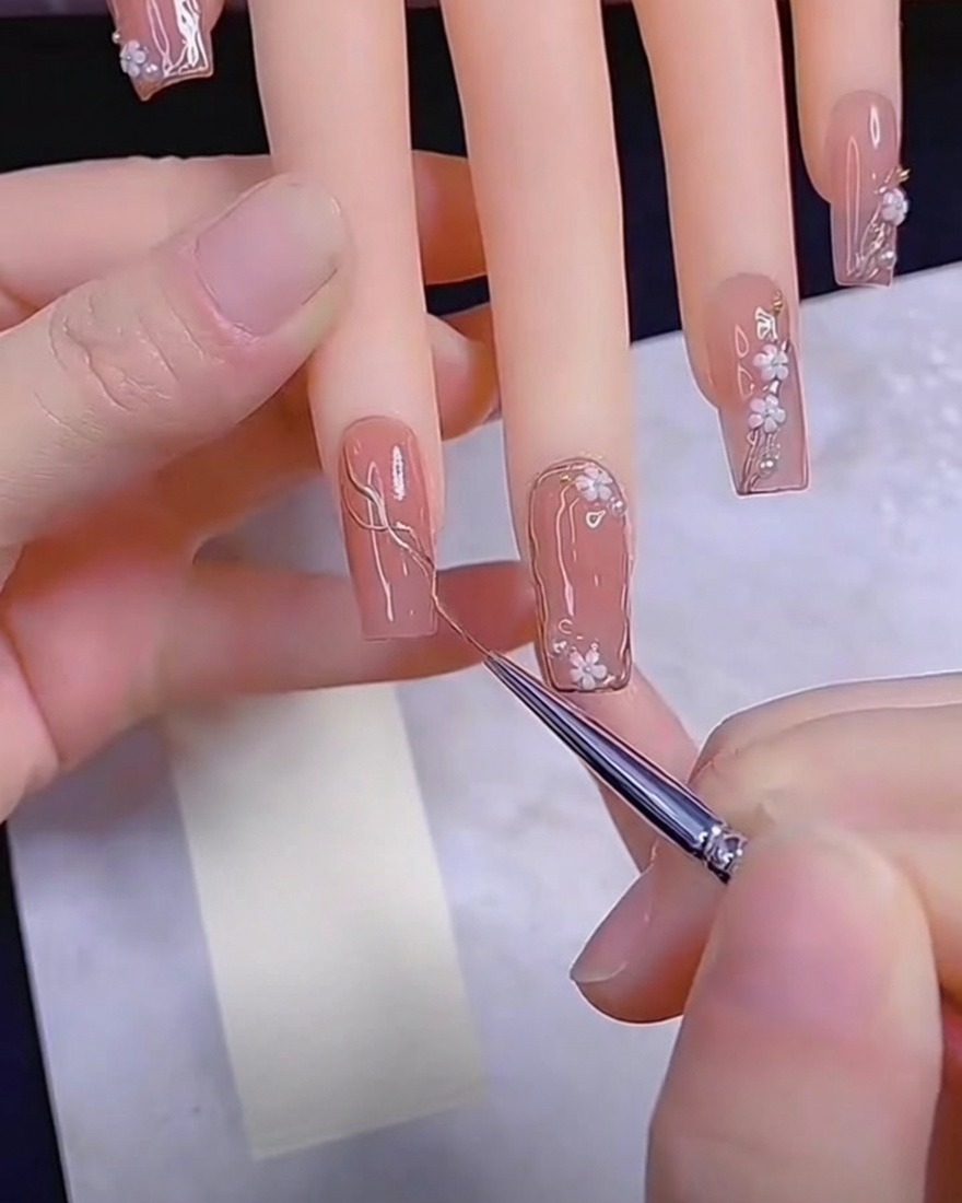 Detailpinsel trägt Metallic-Gel auf einen Nude-Nagel auf.