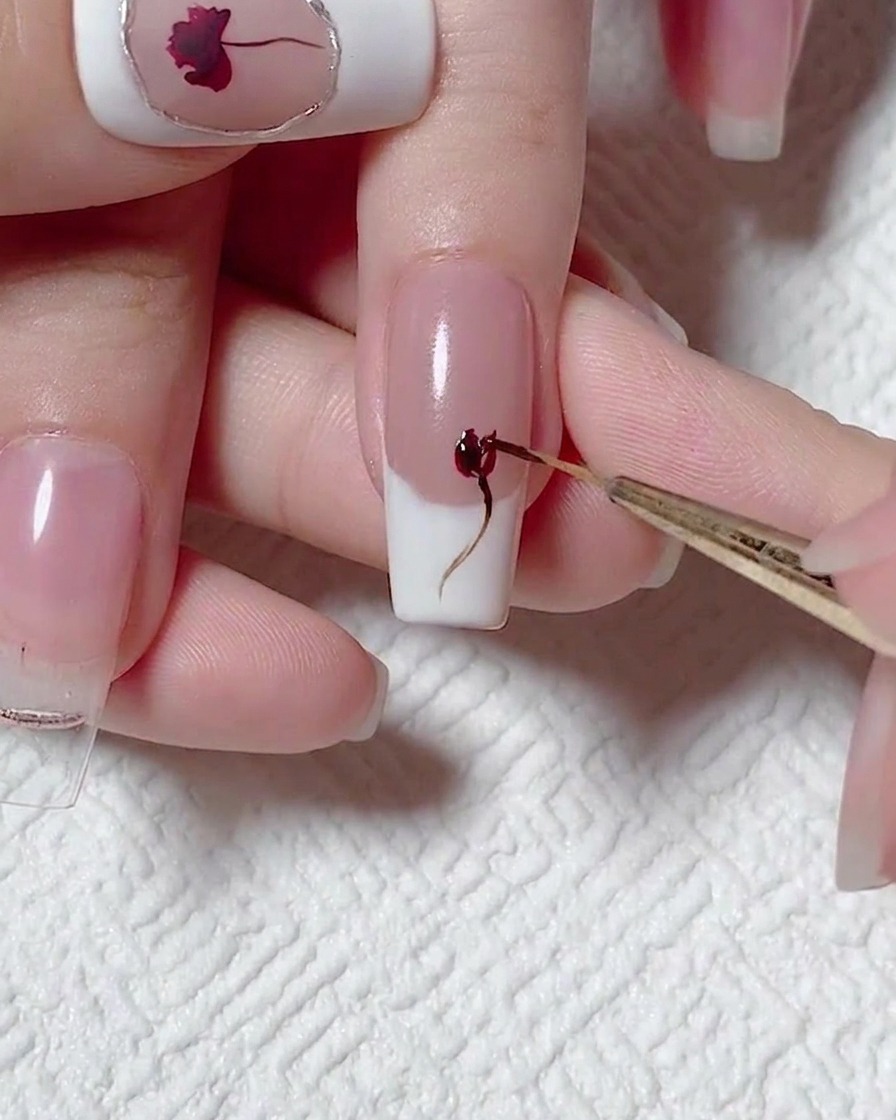 Nahaufnahme eines Detailpinsels, der mit rotem Gel Tiefe in das Rosen-Design einarbeitet.