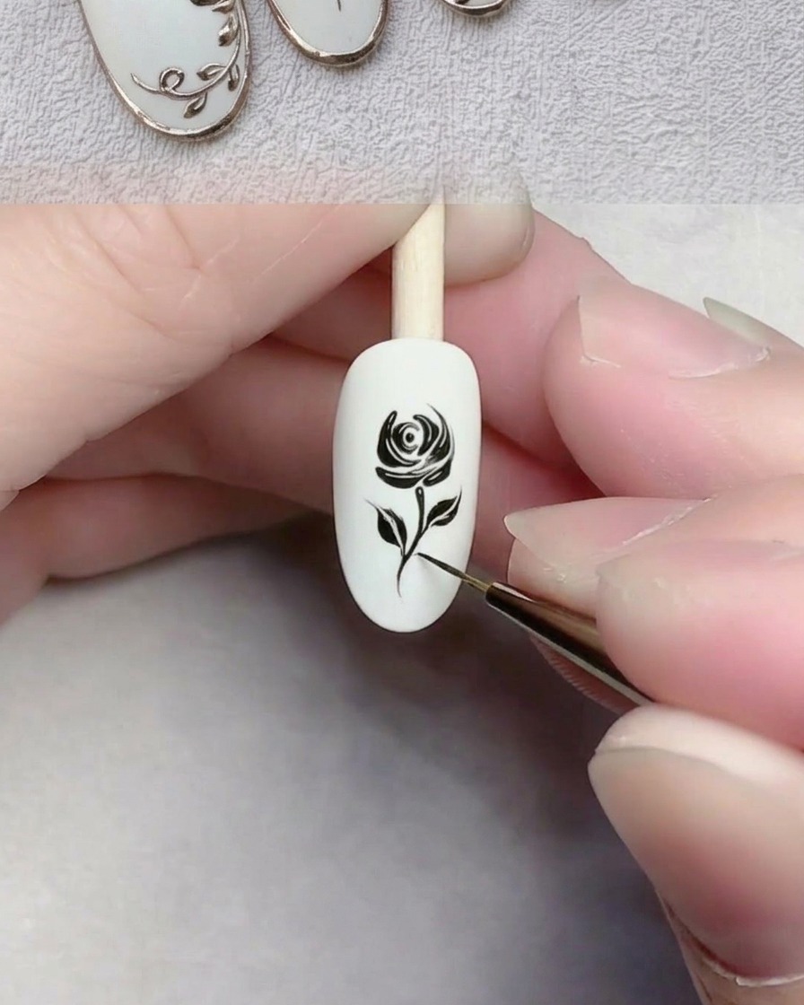 Nahaufnahme eines Liner-Pinsels, der eine dünne schwarze Linie als Stiel auf einem weißen Nagel zieht.