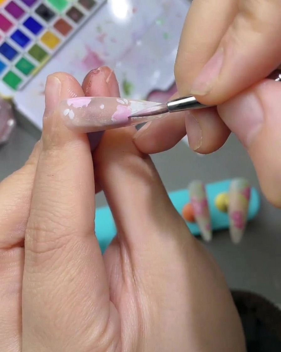 Detaillierte Ansicht von zarten hellgrünen Aquarellblättern neben rosa Rosenblüten.