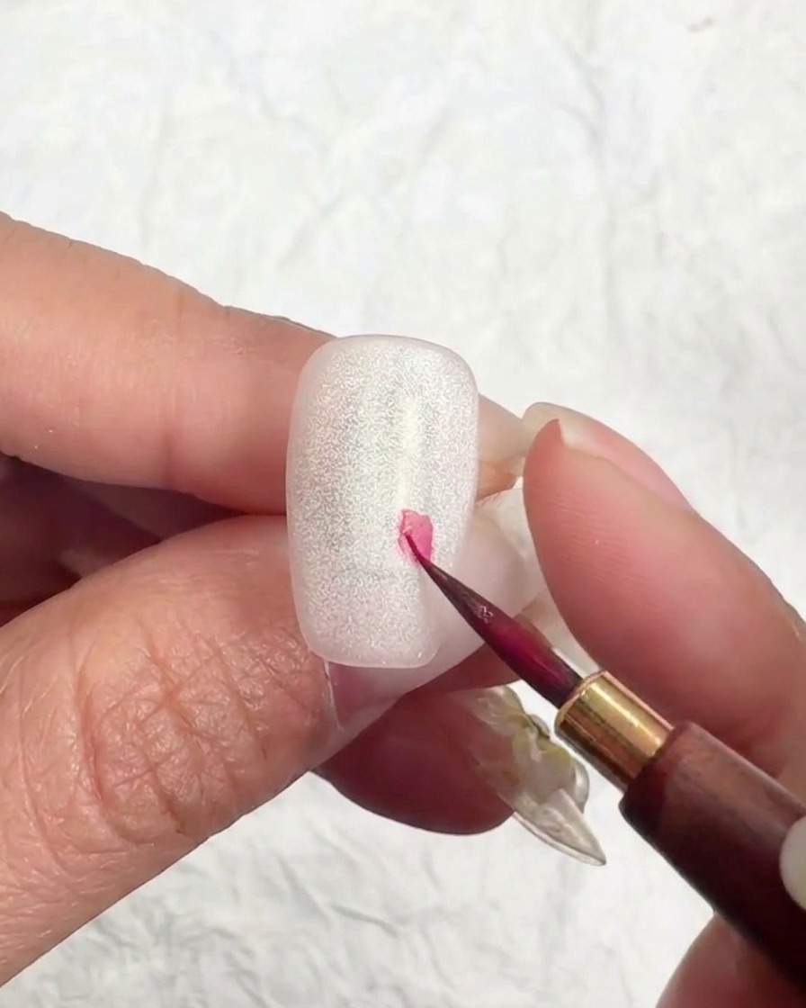 Ein feiner Liner-Pinsel setzt einen kleinen rosafarbenen Punkt für den Beginn einer Kirschblüte.