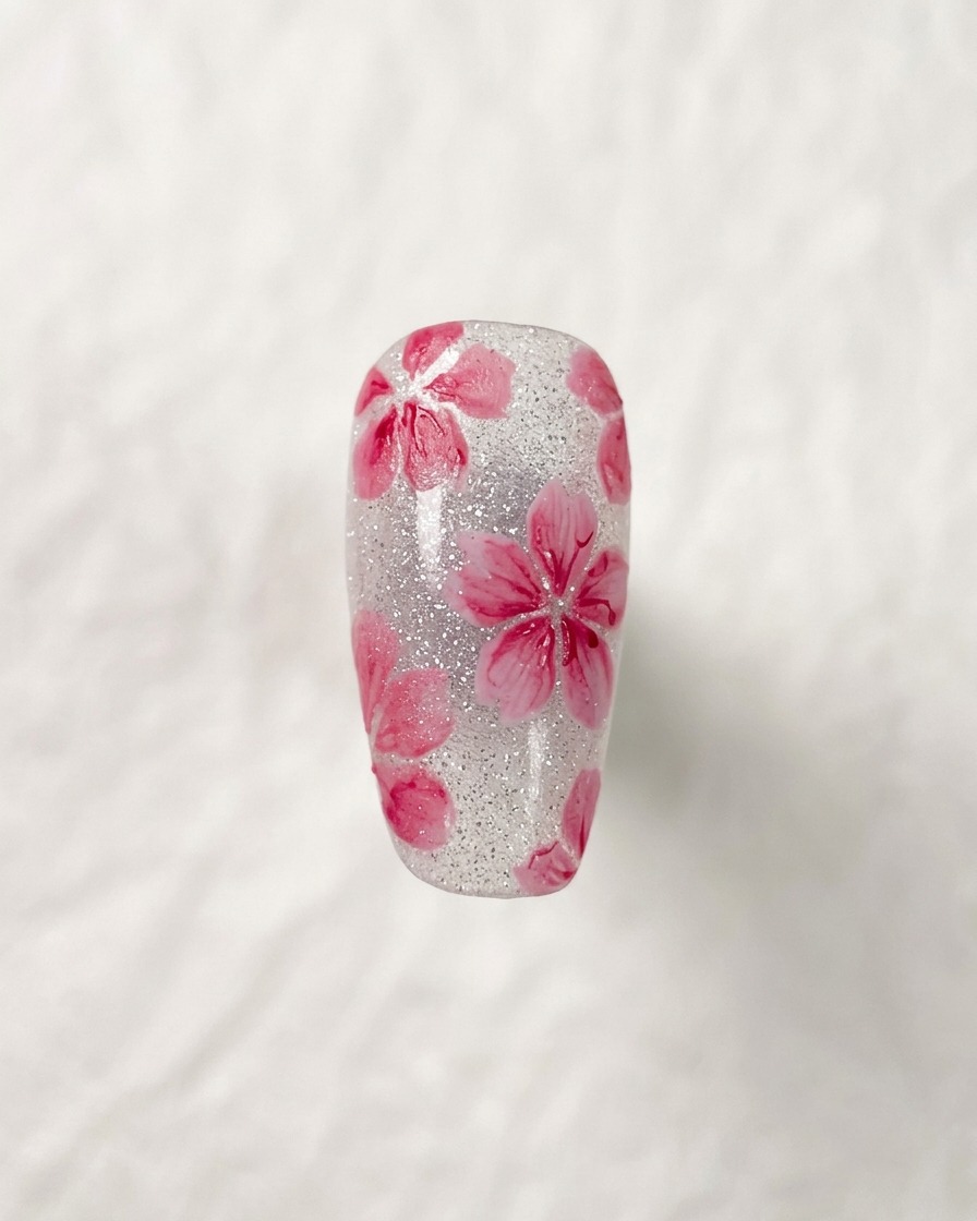 Nahaufnahme eines fertigen Kirschblüten-Nageldesigns mit feinen Details im Blüteninneren.
