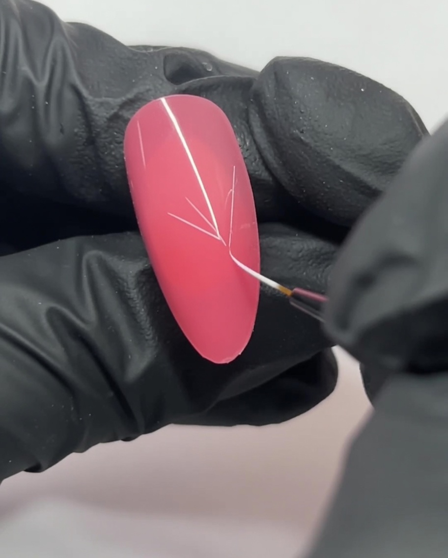 Nahaufnahme eines pinkfarbenen Nagels, auf dem weiße Linien ein Y-förmiges Grundgerüst bilden.