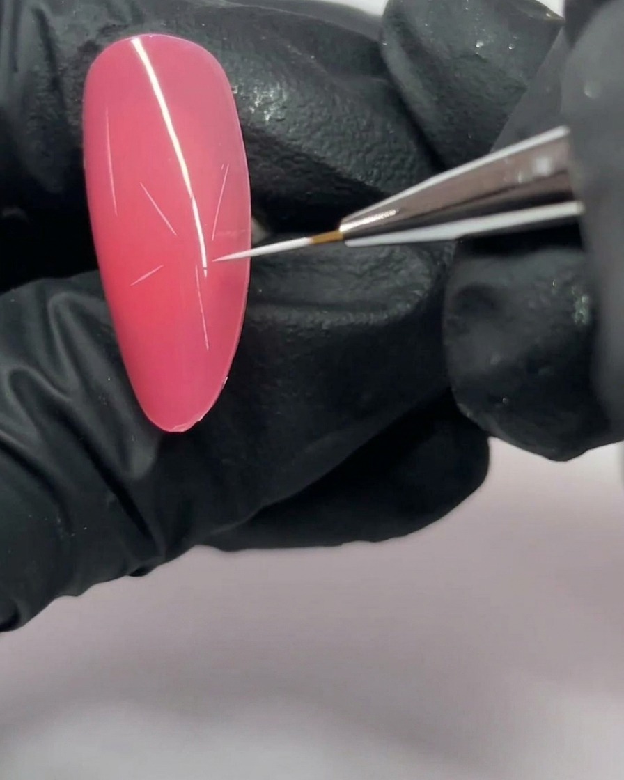 Nahaufnahme eines pinkfarbenen Nagels mit einer fünfzackigen Sternstruktur in Weiß.