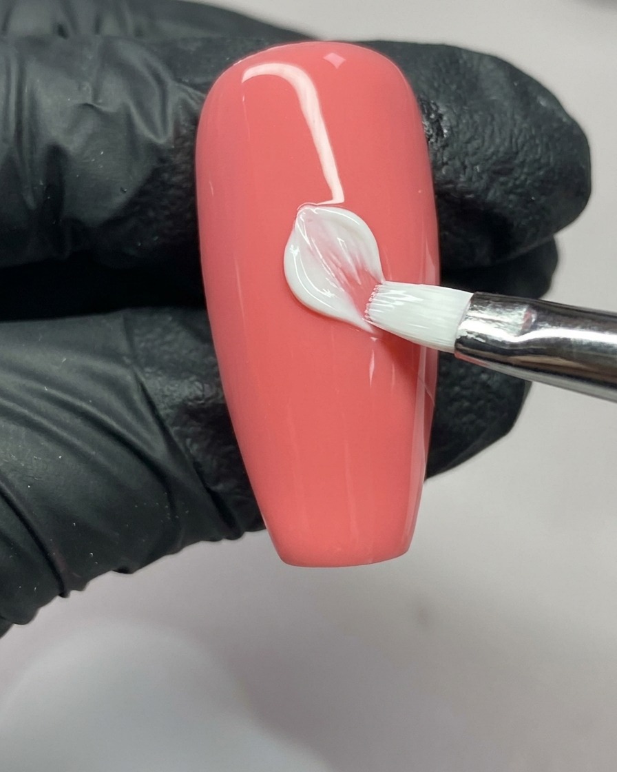 Ein Nagelkunstpinsel vervollständigt die rechte Seite eines Blütenblattes und zeigt die V-Form an der Spitze.