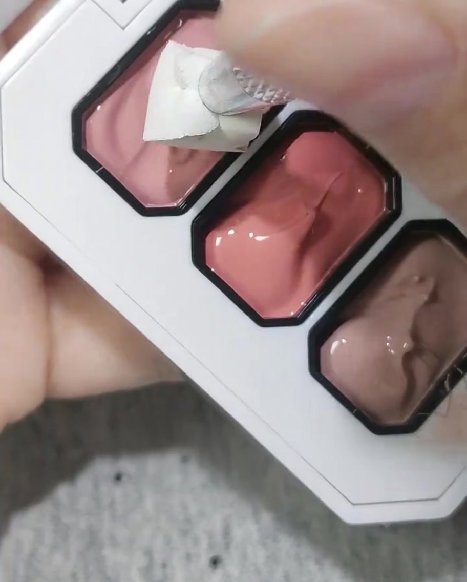 Ein Kosmetikschwämmchen wird verwendet, um rosa Gel auf eine Nagelspitze aufzutupfen.