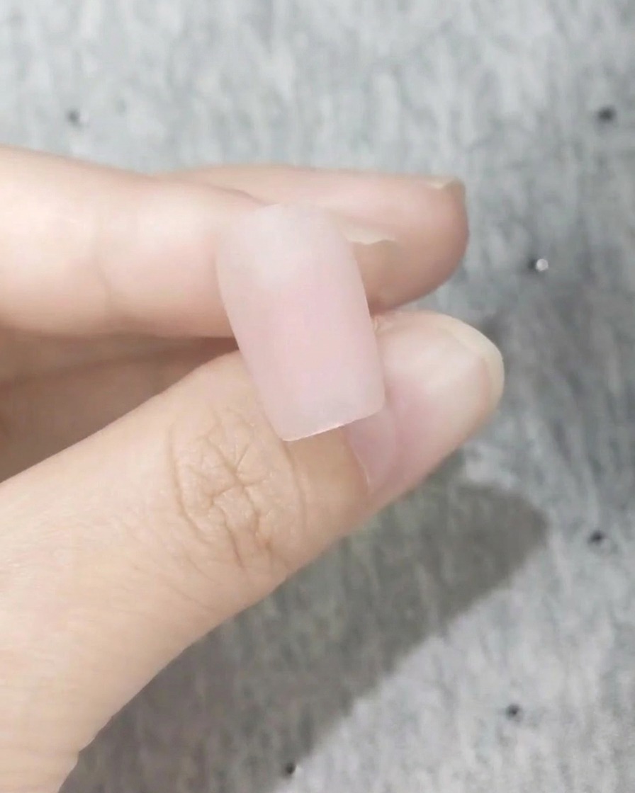 Nahaufnahme eines perfekt glatten Nagels mit einem gefrosteten matten rosa Finish.