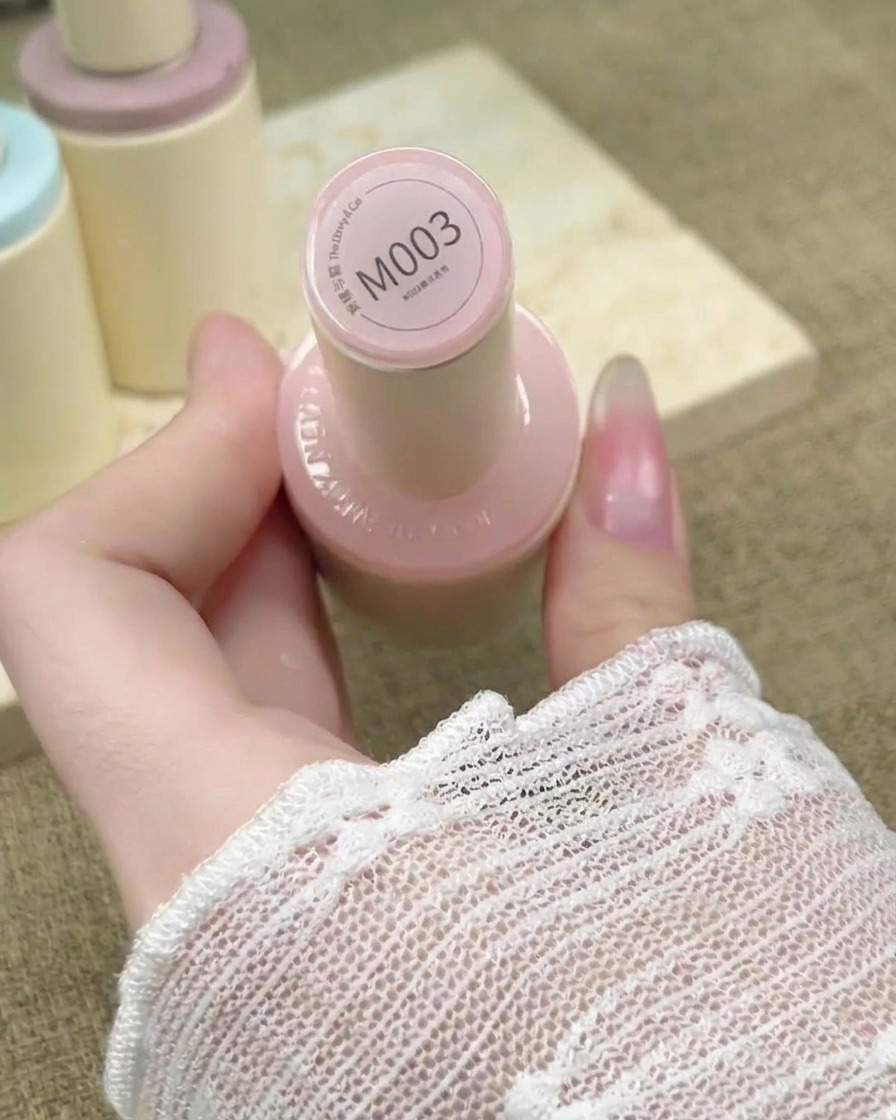 Ein Nagelpinsel trägt ein transparentes, nudefarbenes Gel auf einen verlängerten Nagel auf.