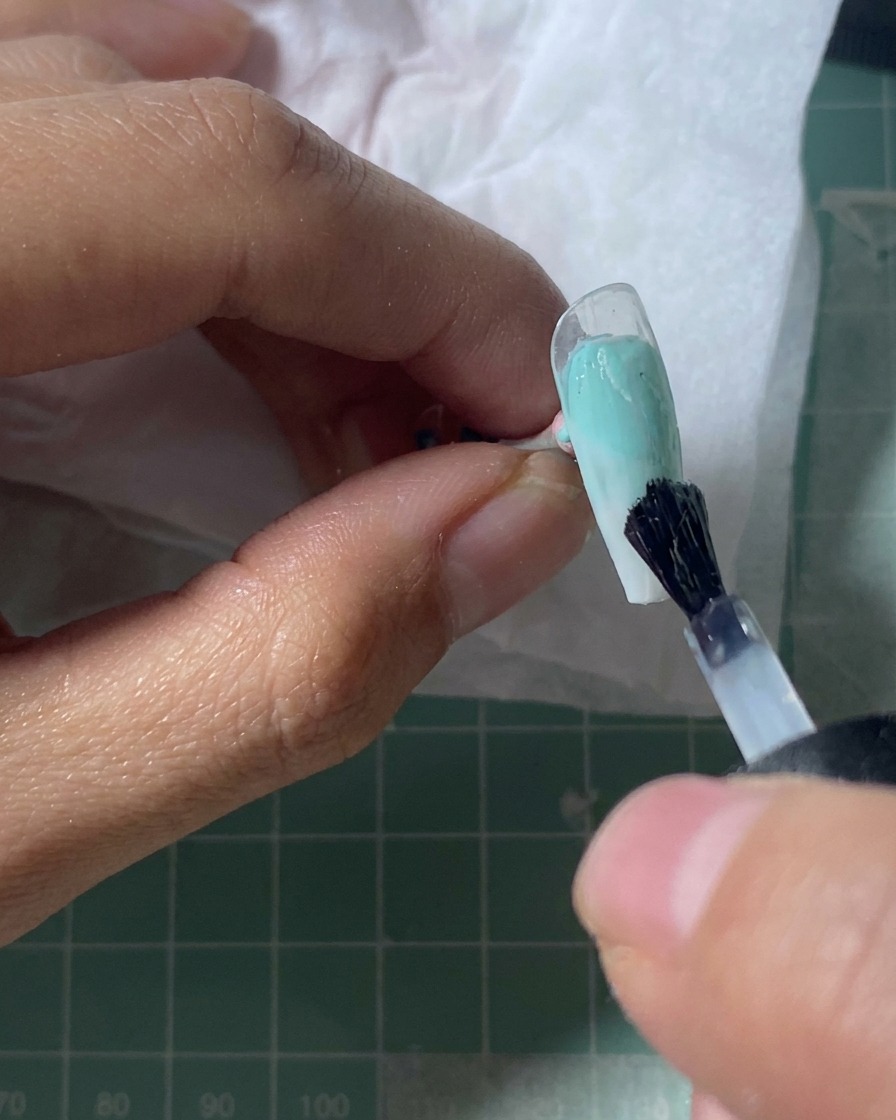 Ein Nageltip unter einer UV-Lampe mit einer glänzenden Oberfläche.